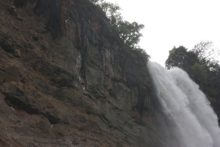 Bungelend aan een touw naast de waterval